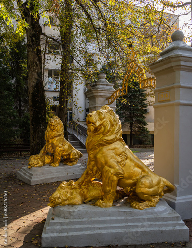 Arch with Figures of two golden lions on huge slabs. Medical park of resort town Goryachiy Klyuch. Monument of architecture. Arch was built in 1914. Under front paws of lions are dead wild boars.. photo