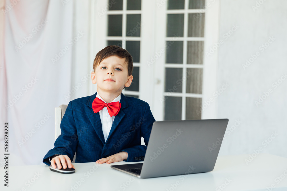 at school in a room in the classroom education online boy sitting at a laptop at a table at school in a room in the classroom education online boy sitting at a laptop at a table