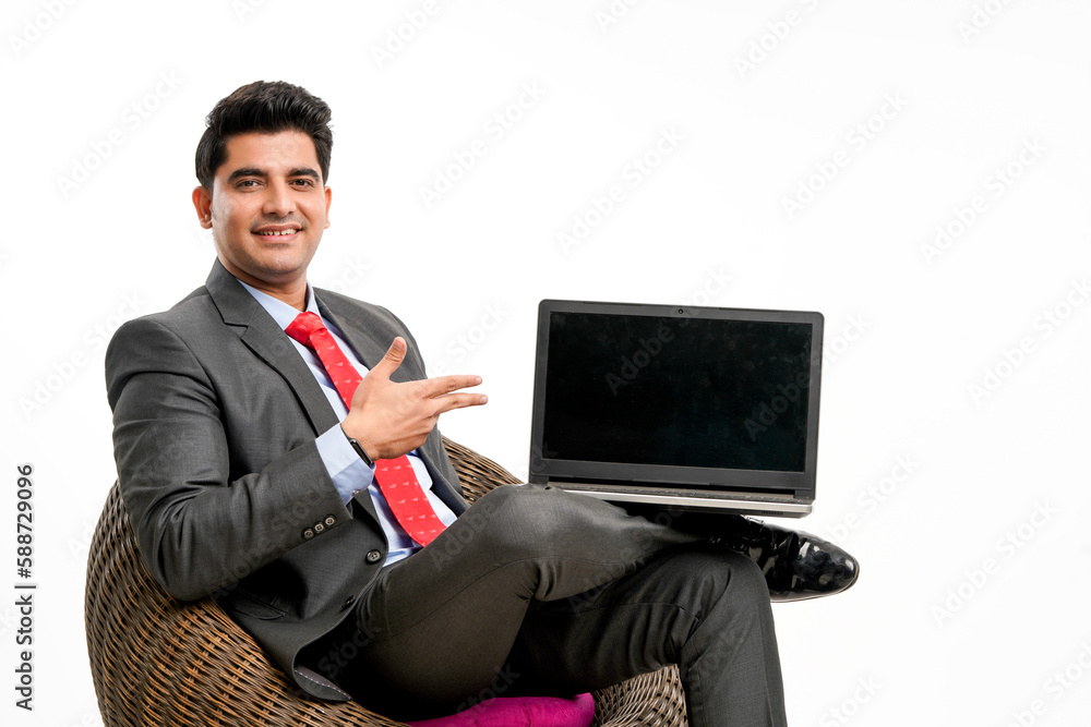 Young indian businessman sitting on chair and showing laptop screen.
