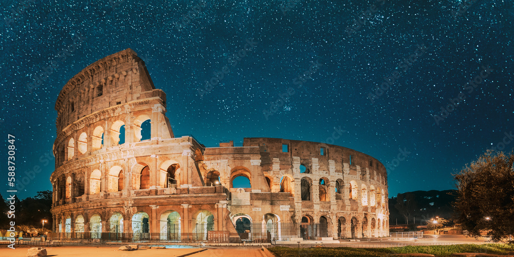 Rome, Italy. Colosseum Also Known As Flavian Amphitheatre In Evening Or Night Time. Travel Italy. Bright Blue Night Sky. Amazing Night Starry Sky Background.