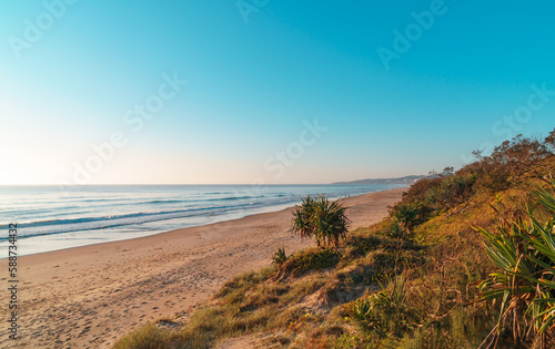 Beautiful wide panorama of the Peregian Beach nestled against the dunes of a pristine white sand beach with surfing breaking waves on the Sunshine Coast, Queensland, Australia.