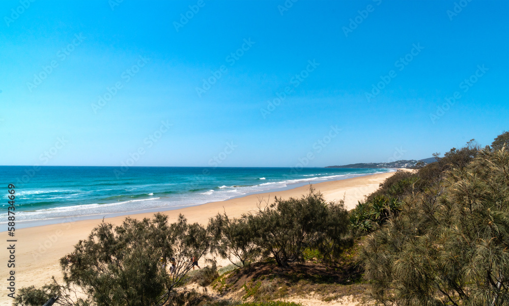 Amazing wide panorama of Peregian Beach on a sunny day. Exotic beach background with blue turquoise water visible from the hill. Beautiful travel destination. Noosa, Sunshine Coast, Australia.