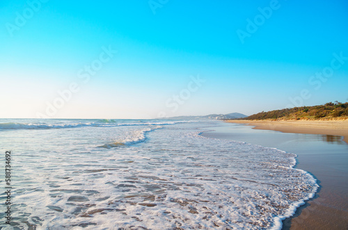Fototapeta Naklejka Na Ścianę i Meble -  Beautiful panorama of the Peregian Beach nestled against the dunes of a pristine white sand beach with surfing breaking waves on the Sunshine Coast, Queensland, Australia. 