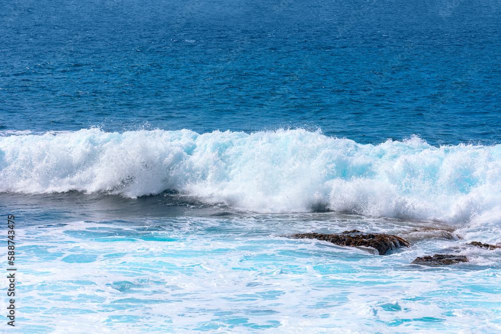 Ocean wave splashing . White waves in blue water Ocean wave splashing . White waves in blue water