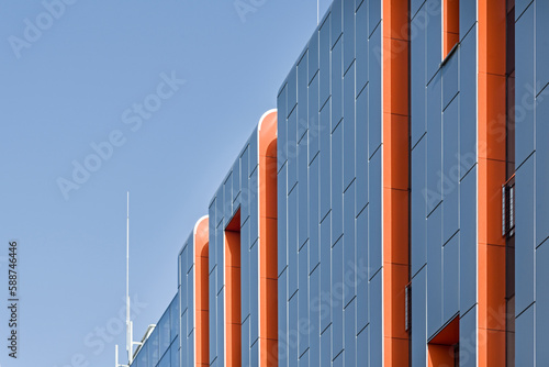 Kolorowy detal na elewacje obiektu, budynku. Materiał z pionowych aluminiowych i pomarańczowych paneli. Nowoczesny budynek