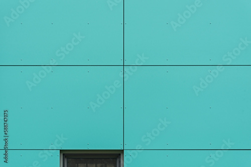 Kolorowa elewacja obiektu, budynku. Materiał z pionowych turkusowych paneli. 