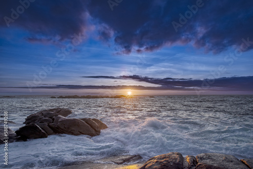 Sunset over some reefs beaten by the waves on the Galician coast of Spain with heavy clouds of water © Toyakisfoto.photos