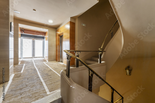 Access portal to a residential building with characteristic stairs with metal railing with golden details and covered floors against renovation works photo