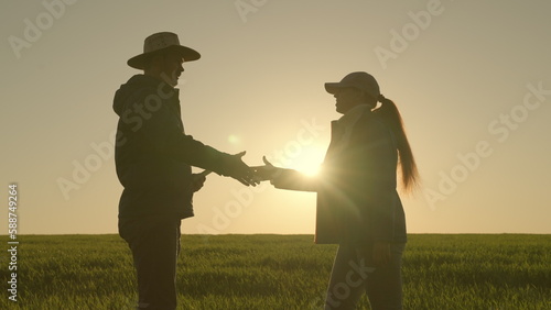 handshake silhouette. farmers businessmen shake hands with each other sunset. have deal. negotiate deal. partnerships. teamwork. Wheat field. Agriculture. farming concept. group people shaking hands photo