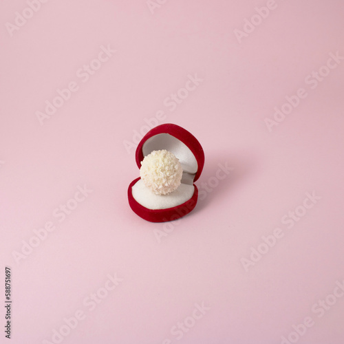 Love composition made of hert red engagement ring box with white chocolates on pink pastel background. Minimal creativ love concept. photo