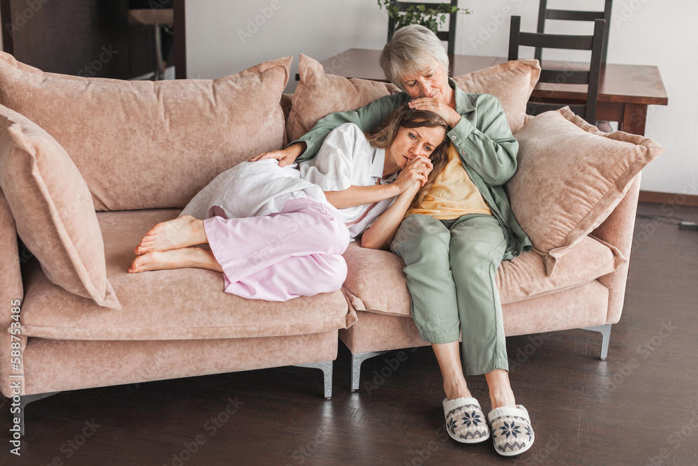 Obraz premium Worried aged mother embracing comforting sad grown up daughter with broken heart family sit on sofa