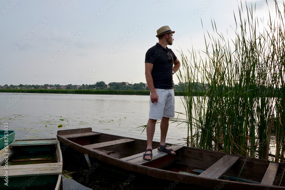 young man in a hat in a boat near the river