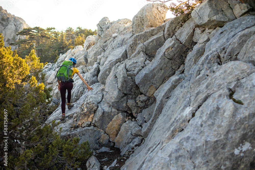 Woman climber with a backpack and a helmet in the mountains. A girl with a backpack walks along a mountain range. adventure and mountaineering concept. mountains of Turkey. Woman climber with a backpack and a helmet in the mountains. A girl with a backpack walks along a mountain range. adventure and mountaineering concept. mountains of Turkey.