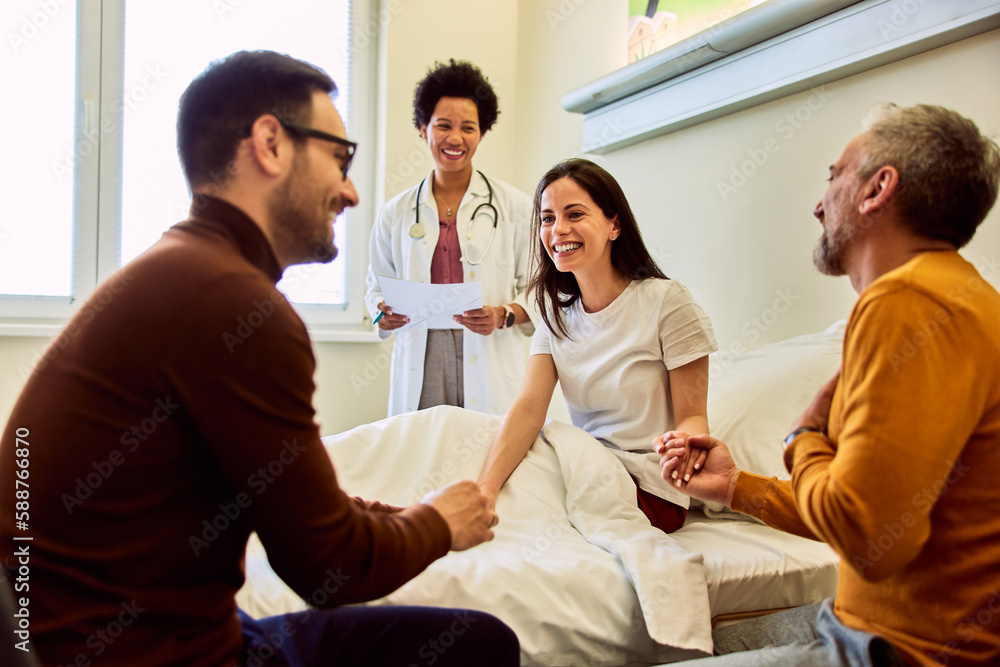 A smiling adult female patient held hands with her family during the visit in presence of the female doctor. A smiling adult female patient held hands with her family during the visit in presence of the female doctor.