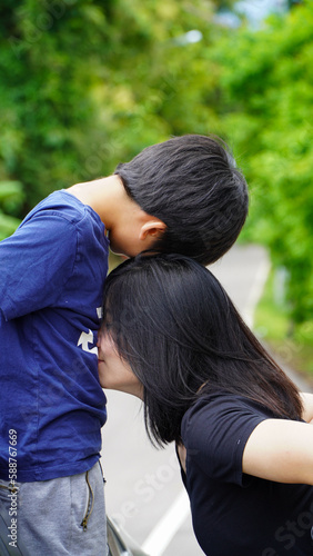 Asian mother kisses son to show affection © Apicha