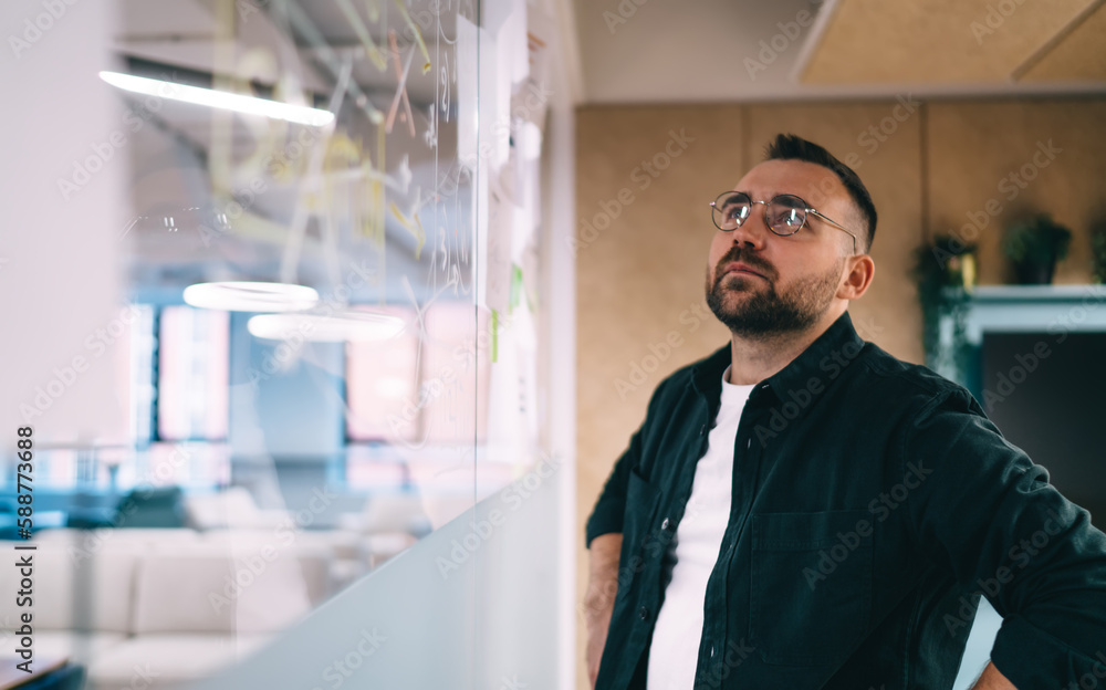 Focused businessman looking at scheme on glass board Focused businessman looking at scheme on glass board