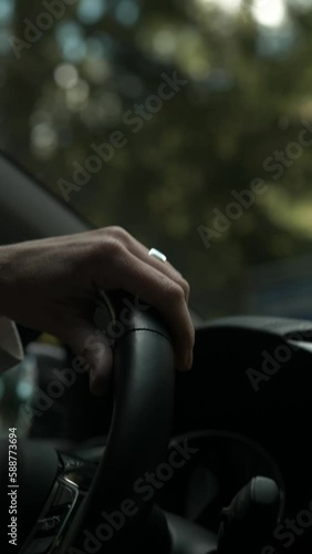Close up of woman driving car with hand on wedding ring on curvy roads in forest with sunlight 