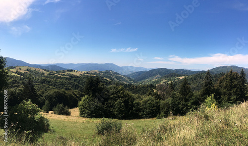 Natural landscape in the mountains in summer. Sunny rural scenery with bright blue sky. Nature protection concept. Green tourism in ukrainian village. Breathtaking mountain view.