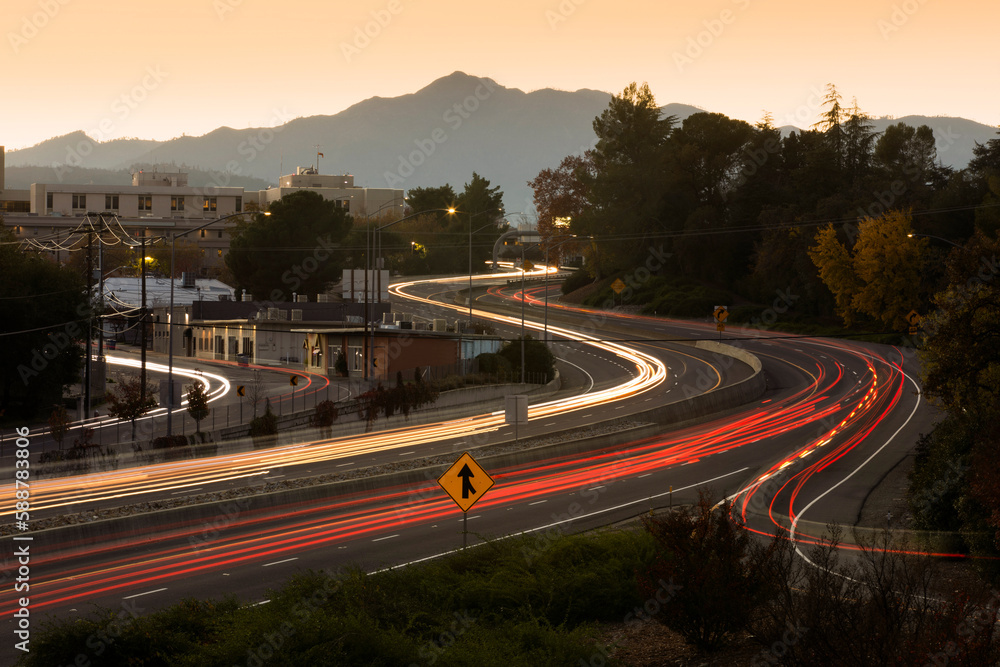 Sunset traffic passes on CA-44 through downtown Redding, California, USA. - obrazy, fototapety, plakaty 