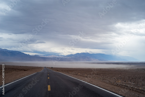 road in the desert with sand cloud 