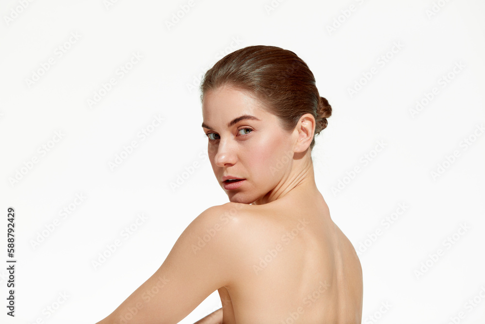 Close up shot of attractive woman with perfect skin looking at camera with no emotion over white background. Back view Close up shot of attractive woman with perfect skin looking at camera with no emotion over white background. Back view