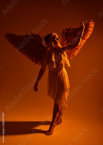 Full length portrait of beautiful blonde woman wearing a fantasy goddess toga costume with feathered angel wings. isolated on white studio background