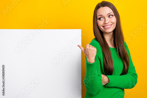 Photo of cheerful pretty girl look direct finger empty space placard isolated on yellow color background