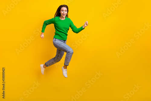 Full length photo of overjoyed cheerful person jumping rush empty space isolated on yellow color background © deagreez