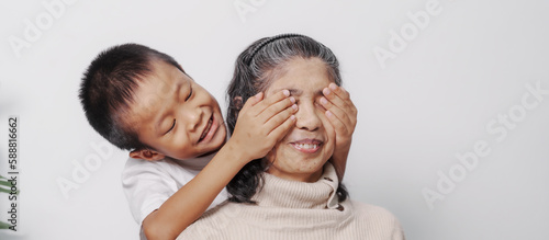 Surprise, close eyes, Asian grandson and grandmother people sitting together at desk.