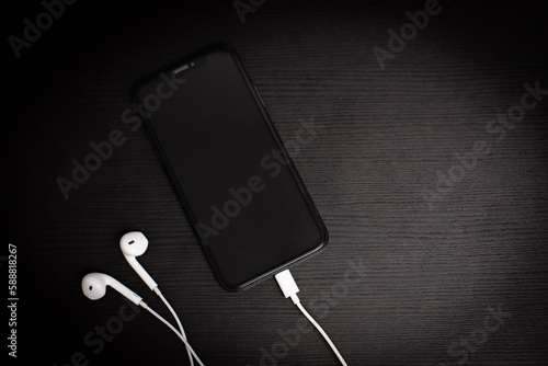 Smartphone on a dark table with earphones