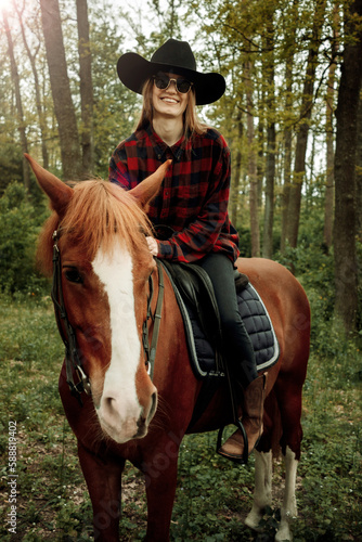 young and beautiful blonde woman with long hair in checked shirt sitting on a chestnut horse