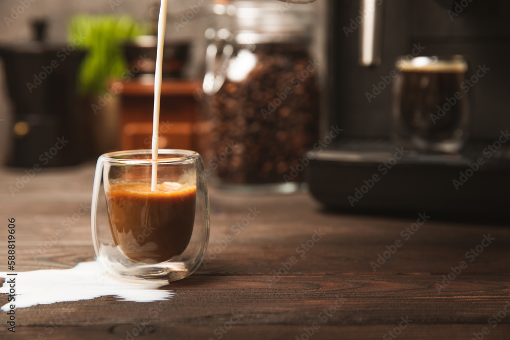 Black coffee in a glass and cream. Pour cream or milk into espresso. Coffee drink on black table background.Barista. Coffee house concept. Place for text. Black coffee in a glass and cream. Pour cream or milk into espresso. Coffee drink on black table background.Barista. Coffee house concept. Place for text.