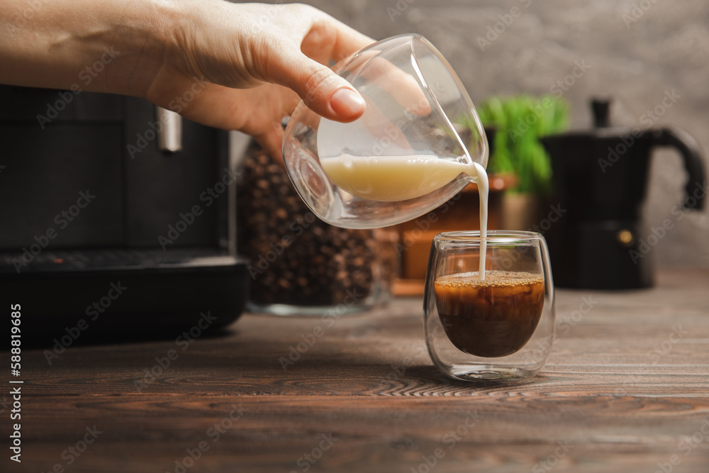 Black coffee in a glass and cream. Pour cream or milk into espresso. Coffee drink on black table background.Barista. Coffee house concept. Place for text. Black coffee in a glass and cream. Pour cream or milk into espresso. Coffee drink on black table background.Barista. Coffee house concept. Place for text.