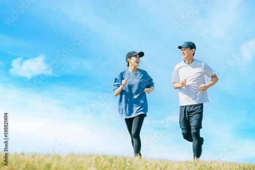 Fotografía 青空の下でジョギングを楽しむ日本人の男女, Japanese man and woman jogging together under a blue sky