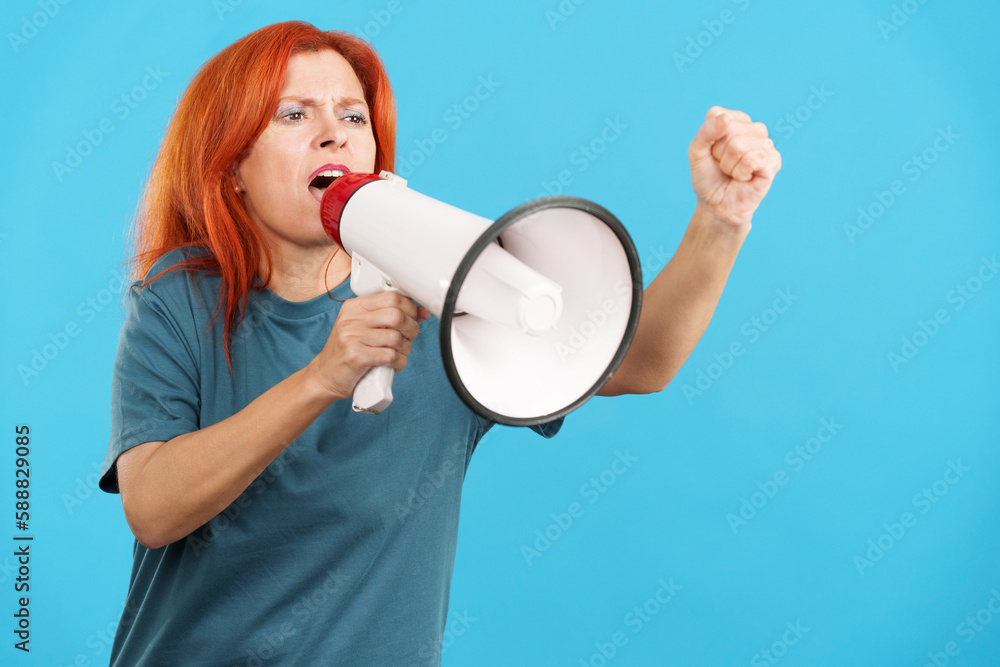 Upset redheaded mature woman yelling using a loudspeaker Upset redheaded mature woman yelling using a loudspeaker