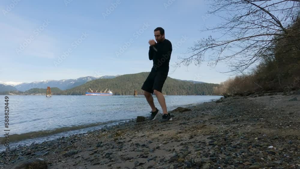 Adult Man Practicing Martial Arts and Shadow Boxing on the beach. Health and Fitness Concept. Port Moody, Vancouver, British Columbia, Canada. Adult Man Practicing Martial Arts and Shadow Boxing on the beach. Health and Fitness Concept. Port Moody, Vancouver, British Columbia, Canada.