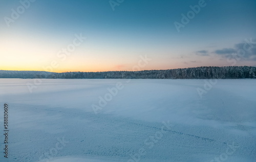 Winter landscape with snow-covered forest  river on a blue sky background