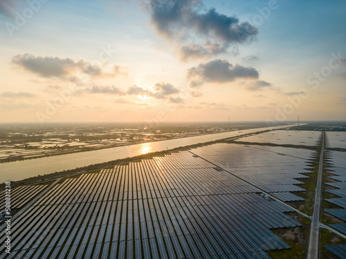 Aerial view of large sustainable electrical power plant with many rows of solar photovoltaic panels for producing clean ecological electric energy in countryside with sunset sky