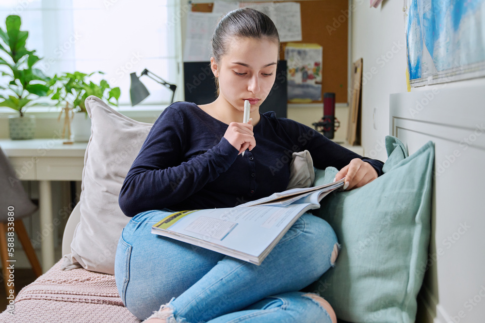 Obraz premium Teenage girl studying at home, sitting on couch at home