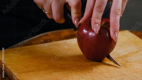 Female hands cut fresh apple with a knife on a cutting board. Peel and slice ripe red apples, delicious apples. The process of making dessert with apples. 4k video