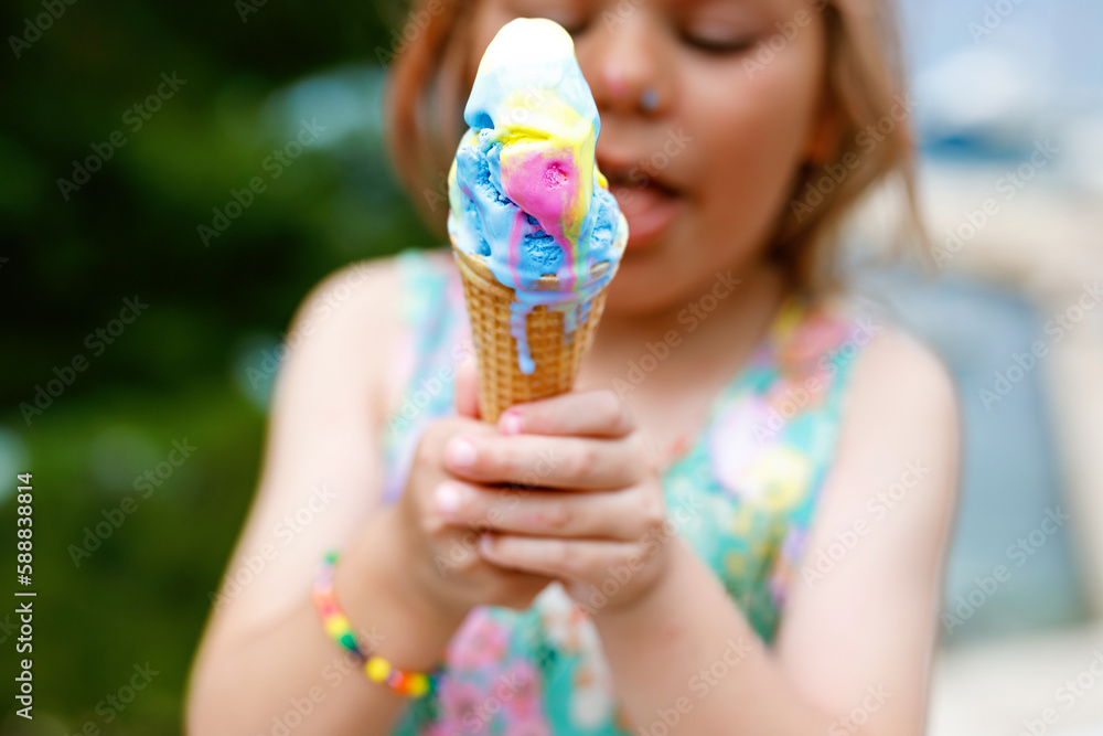 Φωτογραφία Happy preschool girl eating colorful ice cream in waffle cone on sunny summer day
