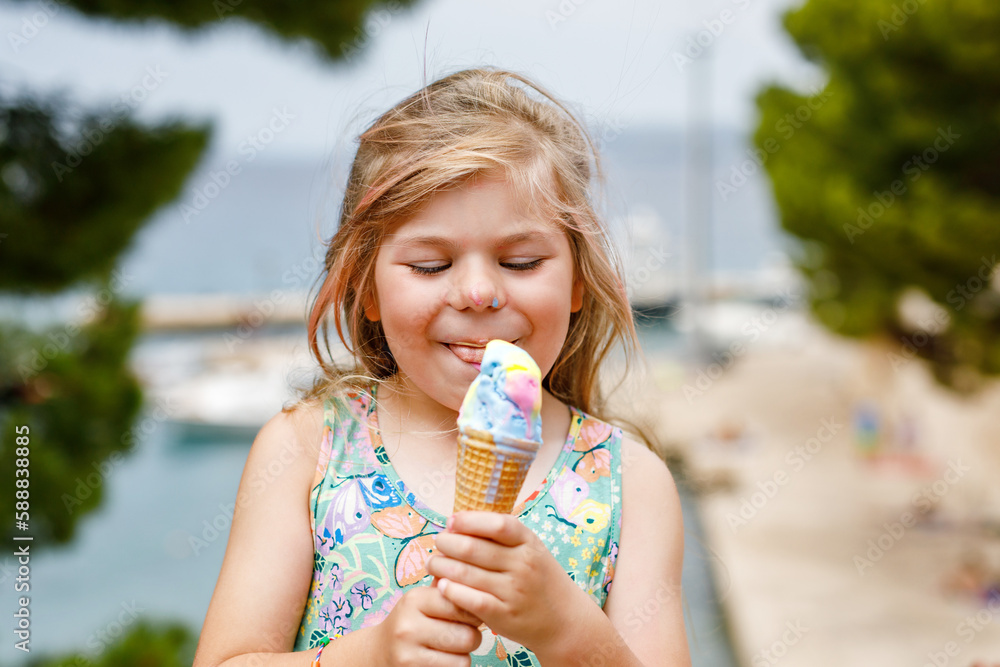 Φωτογραφία Happy preschool girl eating colorful ice cream in waffle cone on sunny summer day