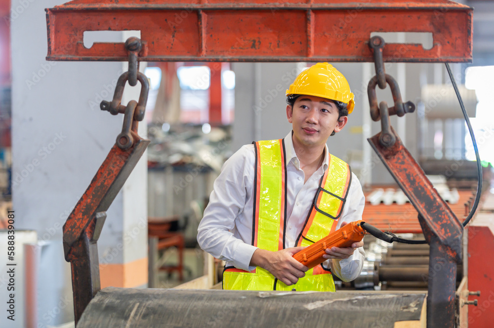 Asian male engineer in uniform inspection warehouse and check control heavy machine construction installation in industrial factory. technician worker check for repair maintenance operation system Asian male engineer in uniform inspection warehouse and check control heavy machine construction installation in industrial factory. technician worker check for repair maintenance operation system