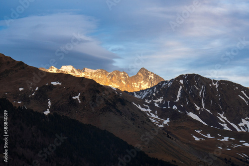 Últimos rayos de sol alumbrando montañas rocosas con algo de nieve photo
