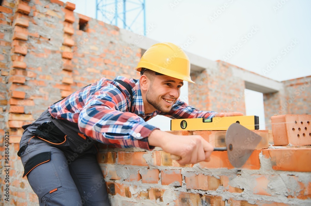 Installing brick wall. Construction worker in uniform and safety equipment have job on building Installing brick wall. Construction worker in uniform and safety equipment have job on building