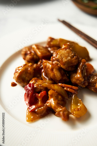 Chicken Manchurian on white plate with chopsticks. White marble background. Sweet and sour Chinese chicken recipe 