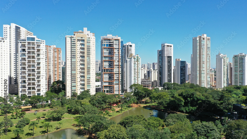Fototapeta premium Wonderful panoramic view of Flamboyant Park with lakes and tropical trees surrounded by modern residential apartments in Goiania, Goias, Brazil in April, 2023. 