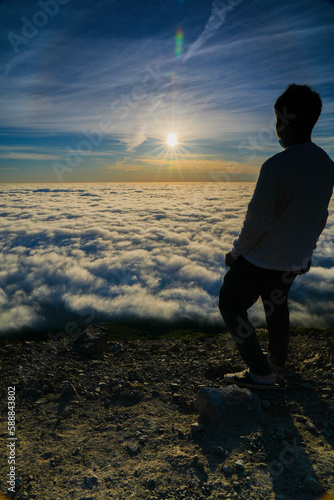 Silhouette of Man Standing on Mountain Above Clouds at Sunrise