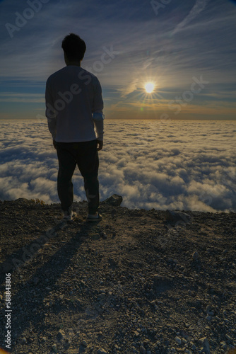 Silhouette of Man Standing on Mountain Above Clouds at Sunrise
