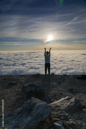 Silhouette of Man Standing on Mountain Above Clouds at Sunrise